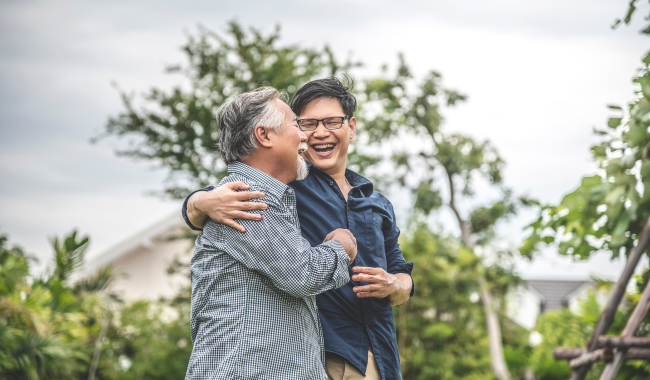 Asian man hugging his elderly father