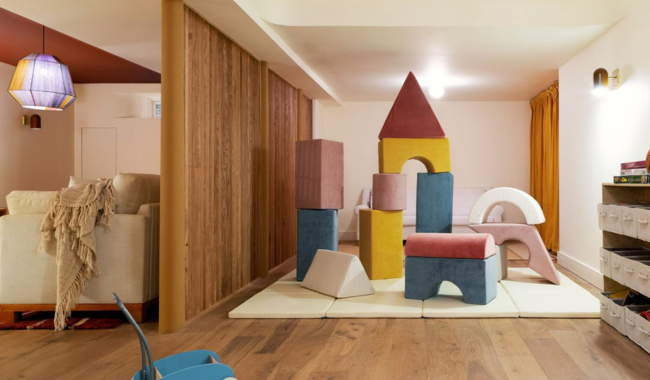 A colorful playroom separated from a living room by a partial wall and open doorway.